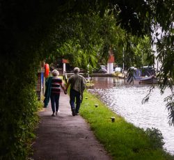 Senior couple walking along lake embankment holding hands